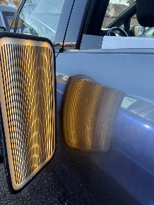Close-up of the reflection board technique showing the exact contour of a car door dent